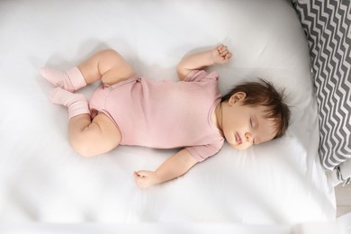Photo of Cute little baby sleeping on cosy bed, top view