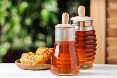 Tasty honey on table against green blurred background