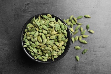 Photo of Bowl of dry cardamom pods on dark grey table, top view