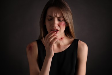Woman with facial injuries on black background. Domestic violence victim