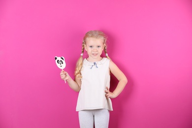 Photo of Cute little girl with candy on color background