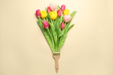 Photo of Brush with colorful tulips on beige background, top view. Creative concept