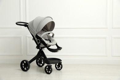 Baby carriage. Modern pram near white wall, space for text