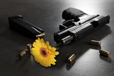 Image of Beautiful flower, bullets and handgun on grey table. Peace instead of war