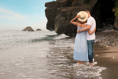 Young couple on beach near sea, back view. Space for text