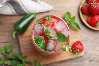 Photo of Spicy strawberry cocktail with jalapeno and mint on wooden table, flat lay