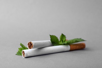 Menthol cigarettes and mint on grey background, closeup. Space for text