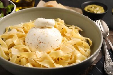 Delicious pasta with burrata cheese in bowl on table, closeup