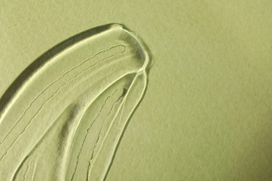 Sample of transparent cosmetic gel on olive background, top view. Space for text