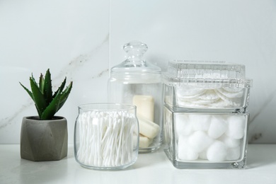 Cotton swabs, pads and balls on white countertop in bathroom