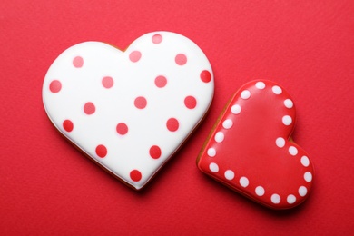Decorated heart shaped cookies on red background, flat lay. Valentine's day treat