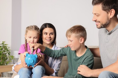 Happy family with money and piggy bank at home
