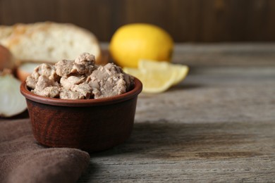 Photo of Bowl of tasty cod liver on wooden table, closeup. Space for text