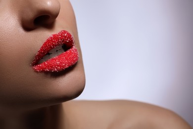 Photo of Young woman with lips covered in sugar on light background, closeup. Space for text