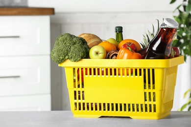 Shopping basket with grocery products on grey table indoors. Space for text