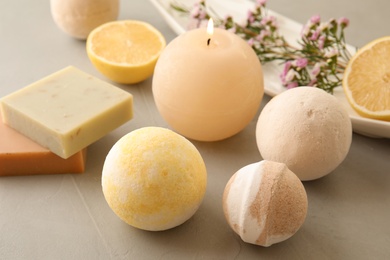 Bath bombs, soap bars and scented candle on grey table