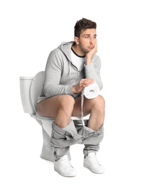 Emotional man with paper roll sitting on toilet bowl, white background