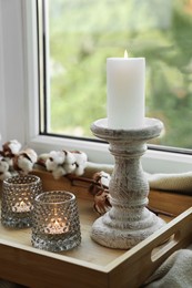 Beautiful candlestick, scented candles and cotton flowers on wooden tray