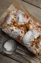 Photo of Delicious yeast dough cake and strainer with powdered sugar on wooden table, flat lay