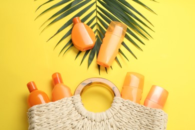 Sun protection products and beach bag on yellow background, flat lay