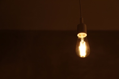 Lamp bulb on dark background. Space for text