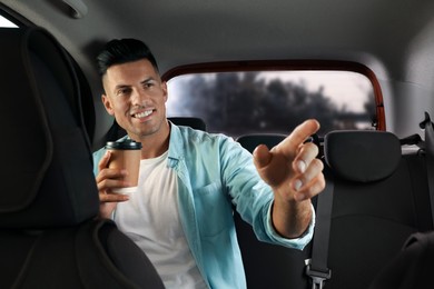Photo of Man with cup of drink in modern taxi