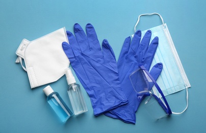 Flat lay composition with medical gloves, masks and hand sanitizers on blue background