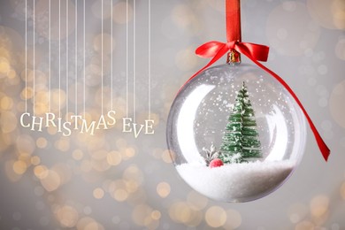 Christmas Eve, postcard design. Decorative bauble against blurred festive lights 