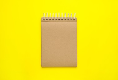 Notebook with brown paper pages on yellow background, top view