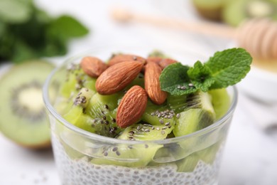 Photo of Delicious dessert with kiwi, chia seeds and almonds in glass, closeup