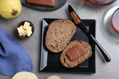 Bread with delicious quince paste on grey table, flat lay