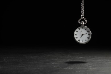 Beautiful vintage pocket watch with silver chain on black background above dark table, space for text. Hypnosis session