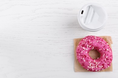 Photo of Tasty frosted donut and hot drink on white wooden table, flat lay. Space for text