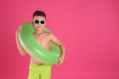 Cute little child in beachwear with bright inflatable ring on pink background. Space for text