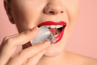 Young woman with ice cube on color background, closeup