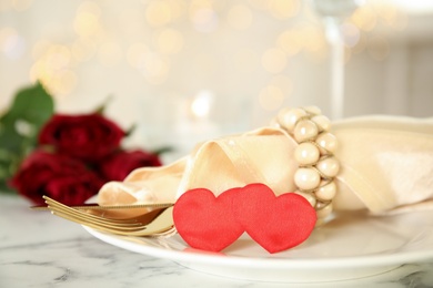 Elegant table setting for romantic dinner against blurred festive lights. Valentine's day celebration