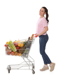 Happy woman with shopping cart full of groceries on white background