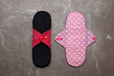 Reusable cloth menstrual pads on brown table, flat lay