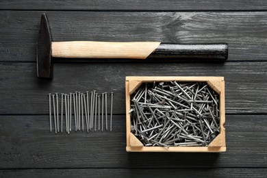 Photo of Hammer and metal nails on wooden table, flat lay
