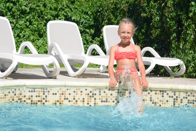 Happy cute little girl having fun in swimming pool on sunny day