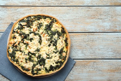 Photo of Delicious homemade spinach quiche on rustic wooden table, top view. Space for text