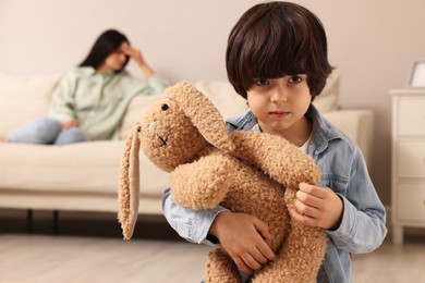 Upset child with toy bunny at home