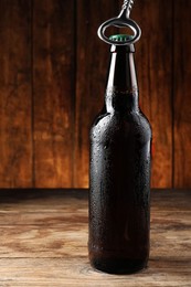 Photo of Opening bottle of beer on wooden table, closeup