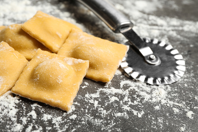 Ravioli and cutter on grey table, closeup. Italian pasta