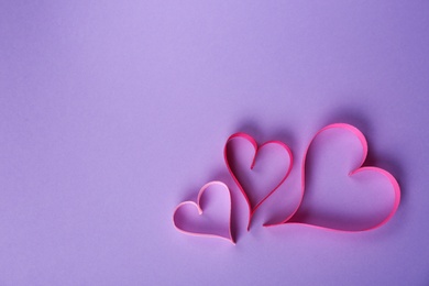 Hearts made of ribbons and space for text on color background, top view