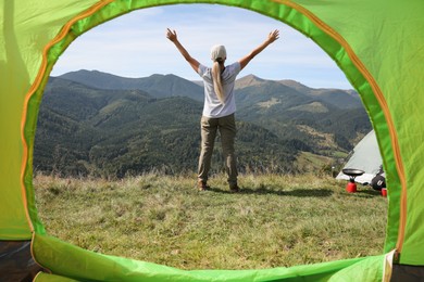 Woman enjoying mountain landscape, view from camping tent
