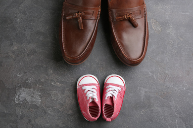 Dad and daughter's shoes on grey stone background, flat lay. Happy Father's Day