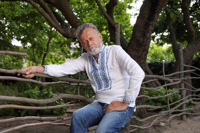 Photo of Senior man in vyshyvanka outdoors. Ukrainian national clothes