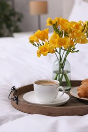 Photo of Morning coffee, croissant and flowers on bed indoors