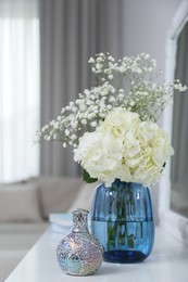 Stylish catalytic lamp with beautiful bouquet on white table in living room. Cozy interior